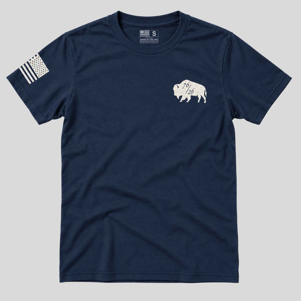 A navy blue short-sleeve t-shirt with a white bison graphic on the left chest and a distressed black-and-white American flag print on the right sleeve, shown against a solid gray background.
