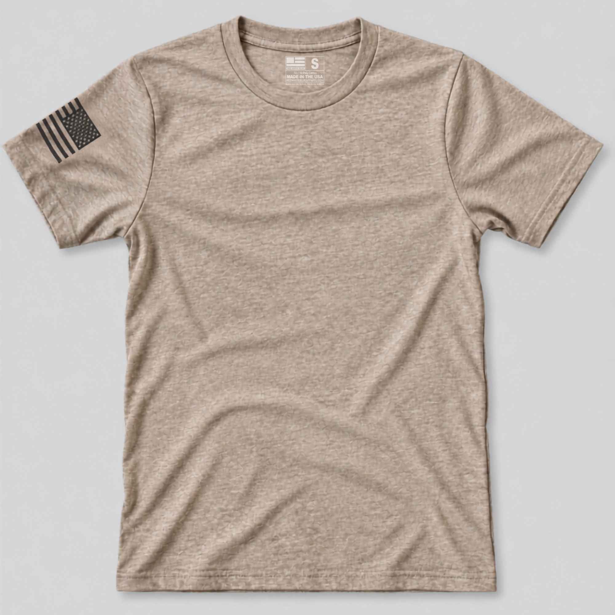 A short-sleeve crewneck t-shirt in heathered tan, featuring a black distressed American flag patch on the left sleeve, laid flat on a light gray background.
