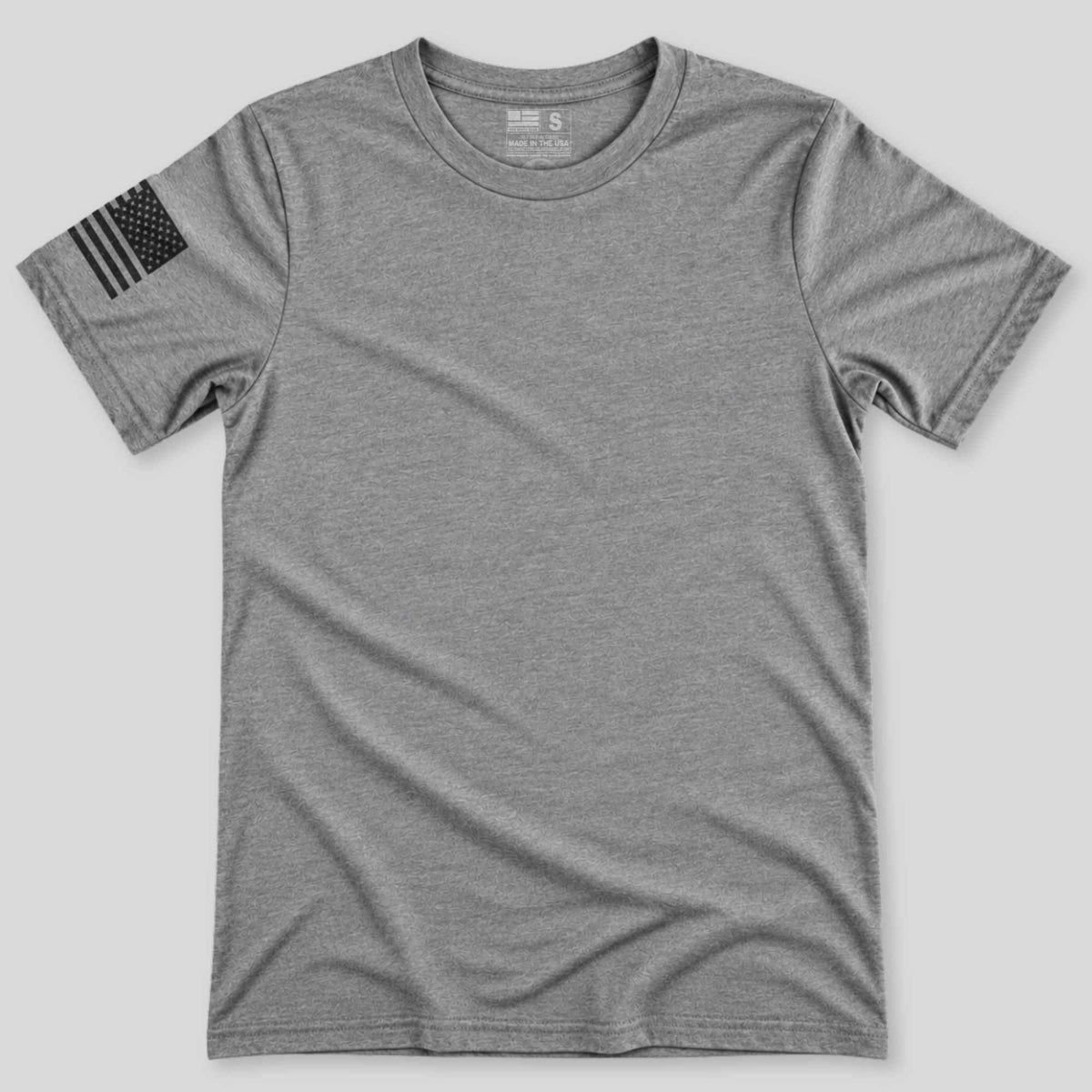 A heather gray short-sleeve crewneck t-shirt with a black distressed American flag graphic on the left sleeve, displayed flat against a light gray background.
