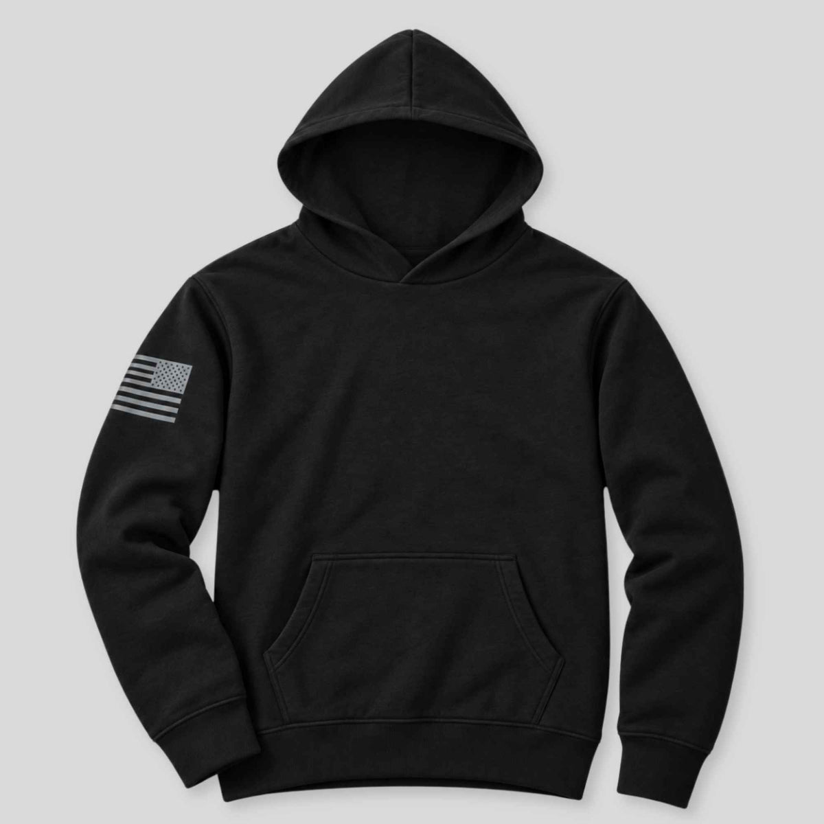 A black pullover hoodie with a gray distressed American flag patch on the left sleeve, displayed against a solid light gray background.